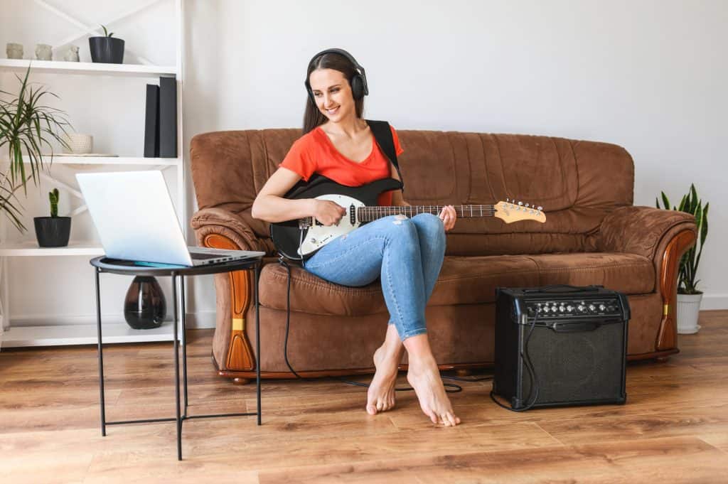 A woman learns to play electric guitar at home