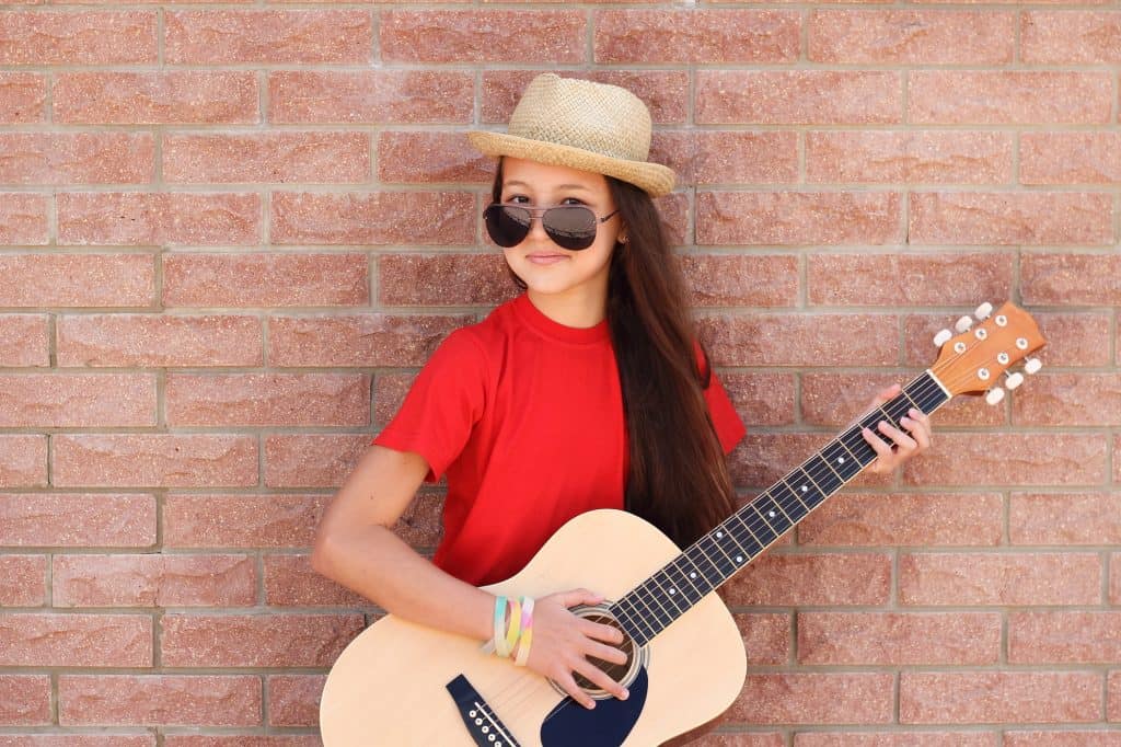 Girl in a red shirt plays on a half size guitar