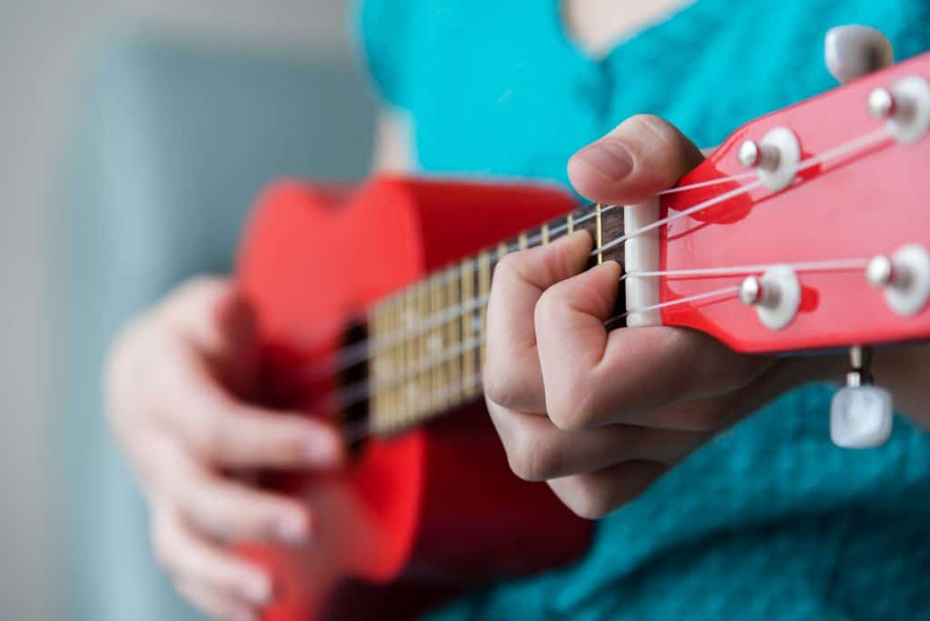 Girl playing on a red soprano ukulele