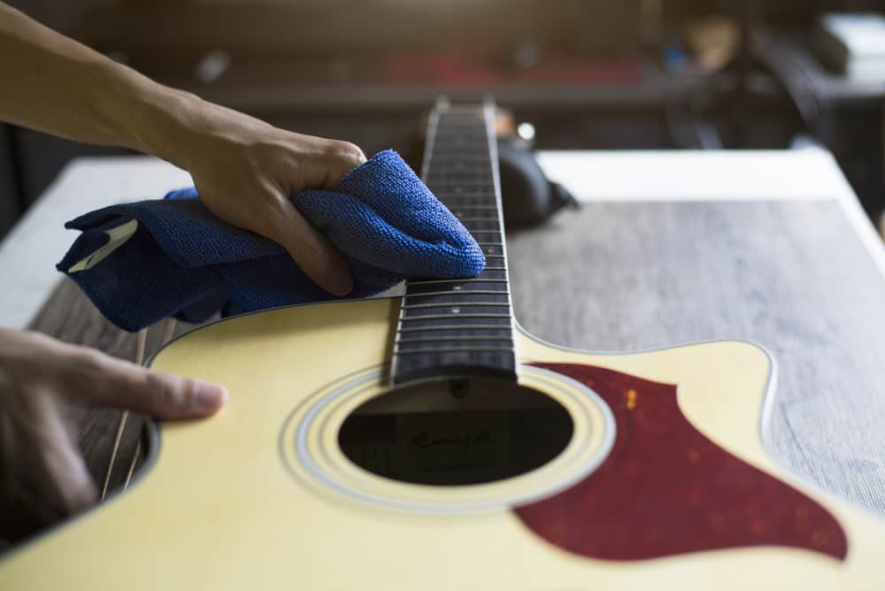 Guitar repairer is cleaning acoustic guitar strings with a cloth