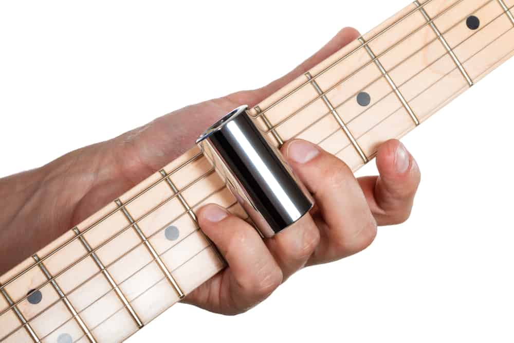 Hands of man playing electric guitar with a slide