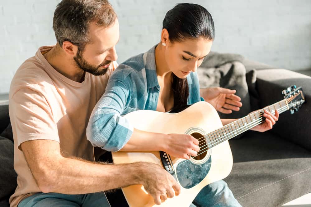 Husband teaching wife to play acoustic gutiar