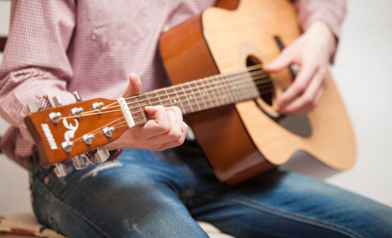 Man in jeans sitting and playing guitar