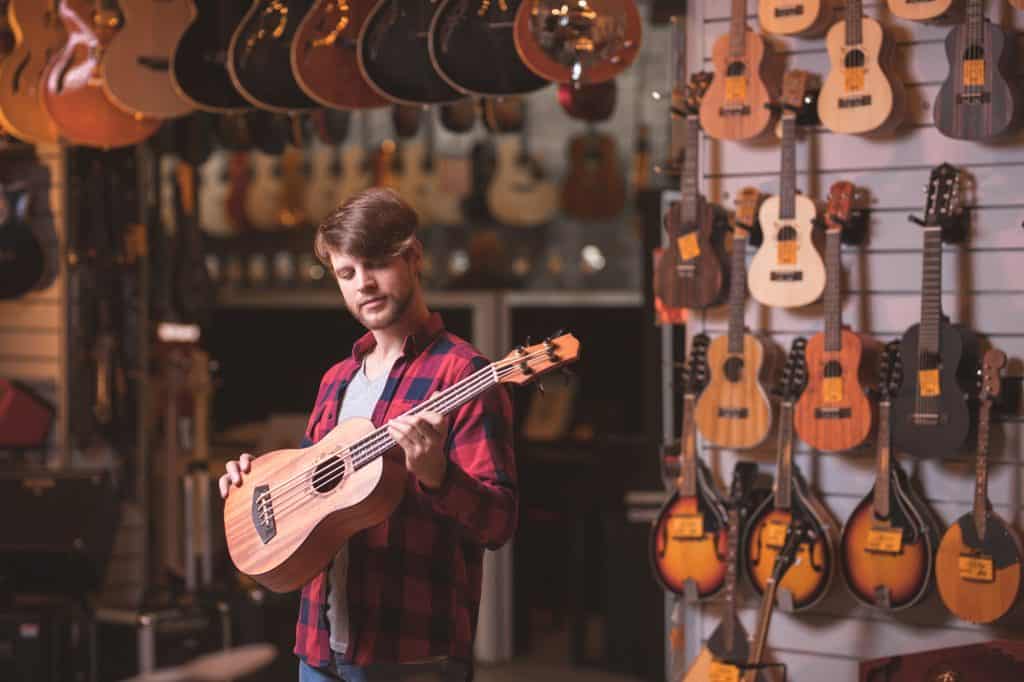 Musician with a baritone ukulele in a music store