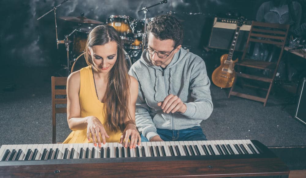 Piano teacher giving music lessons to his student