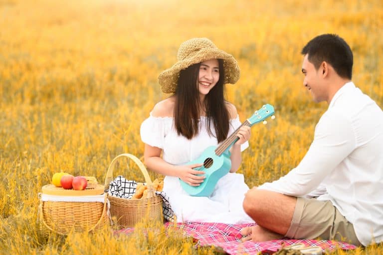 Young asian couple playing ukulele during a picnic